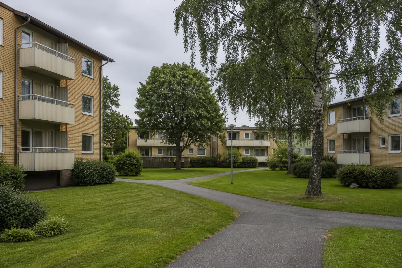 Lägre flerfamiljshus grupperade kring gemensamma gräsgårdar med gångvägar, typiskt för 1970-talsbebyggelsen i Fornhöjden