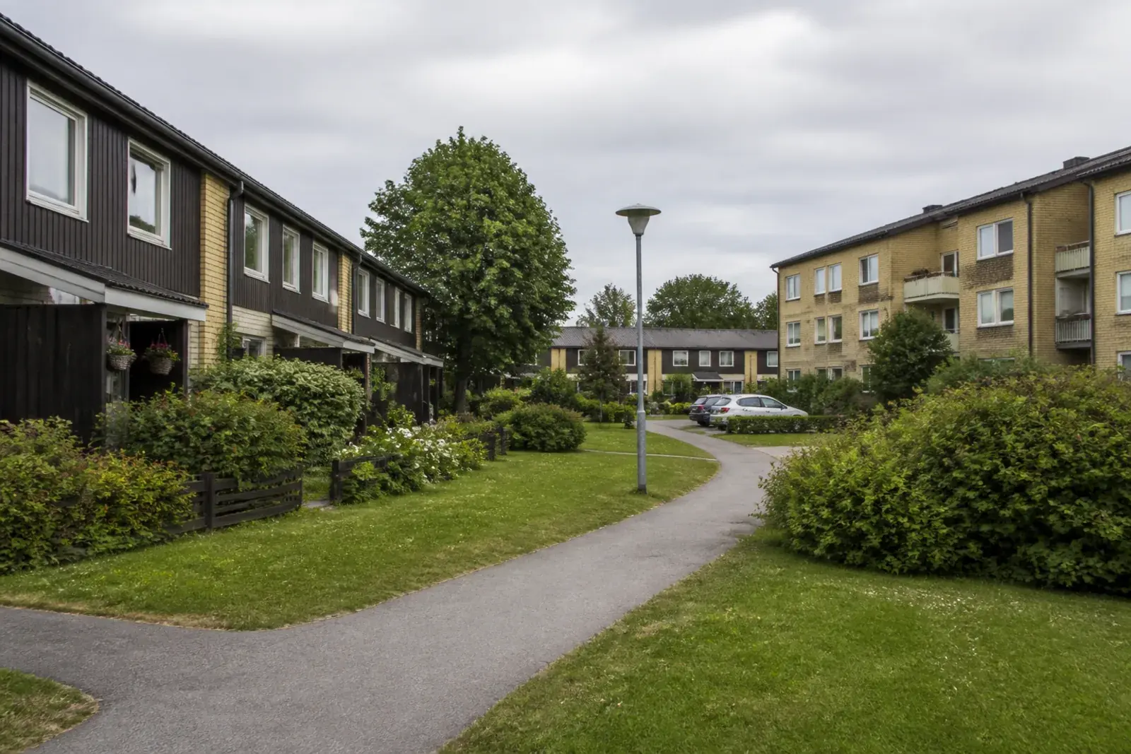 Lägre flerfamiljshus och radhus med gångvägar och grönska, typiskt för bebyggelsen i Hovsjö
