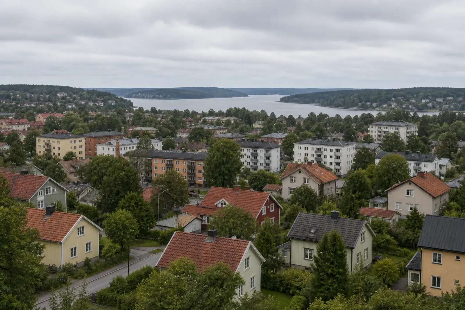 Vy över blandad bostadsbebyggelse med flerfamiljshus, villor och vatten i bakgrunden