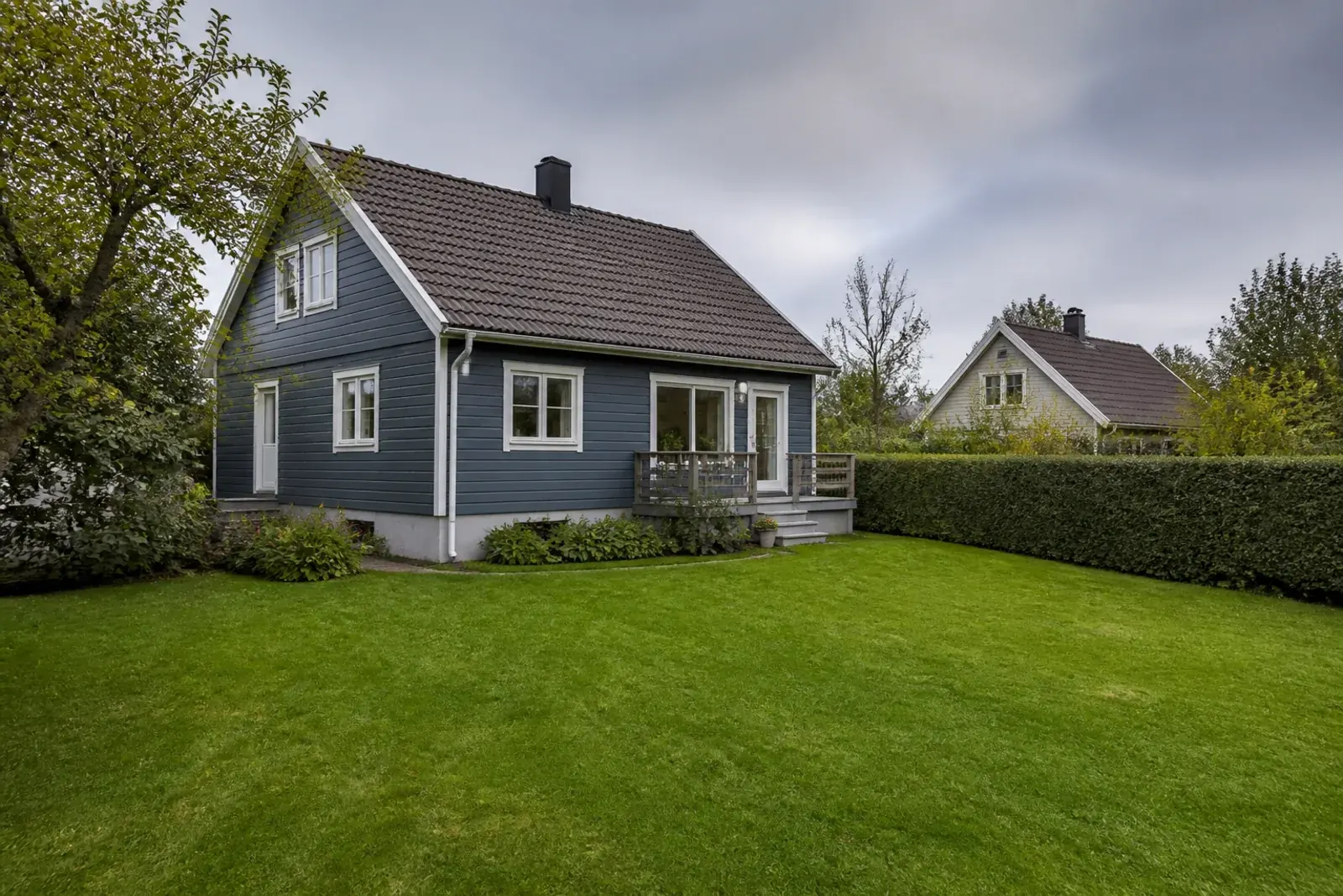 Villa med trädgård en gråmulen eftermiddag, av den typ som värderas inför en försäljning
